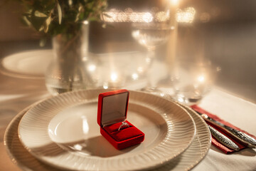 holidays, valentine's day and proposal concept - close up of engagement ring in red box on served...