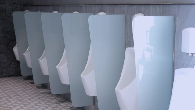 Empty clean mens toilet with ceramic urinals in public place. Interior of modern mens toilet in urban style in restaurant, shopping center or airport. Concept cleanliness and hygiene in public toilets