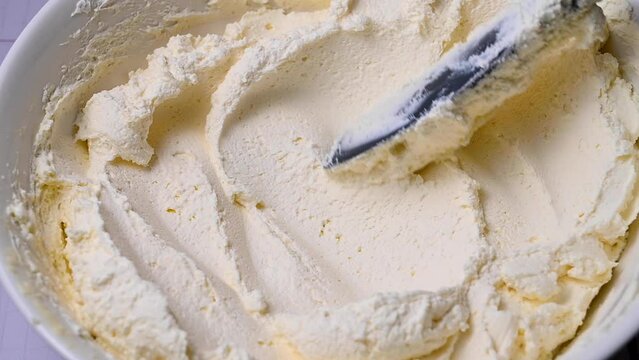 Stirring whipped cream in a bowl, cooking white cream for cake
