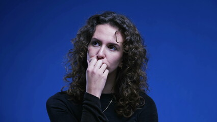 Pensive woman pondering decision with hand in chin thinking deeply about dilemma. 20s female person...