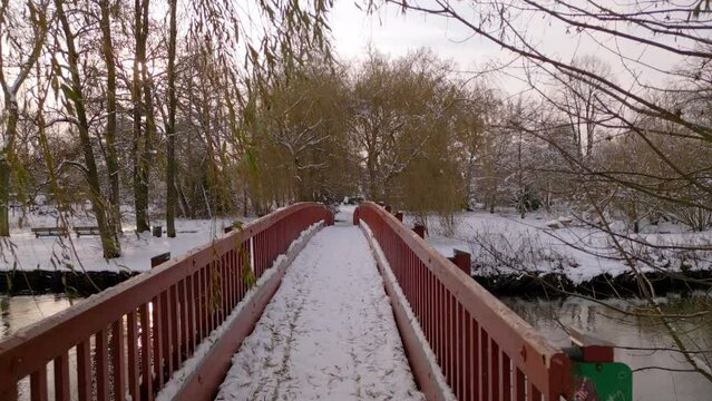 Red wooden bridge over river in snow-covered landscape