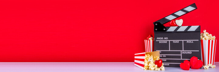 Romantic date on Valentine's Day February 14. Love movie marathon, date at cinema theater. Clapperboard, popcorn buckets, heart decor and chocolates on red background flat lay copy space - obrazy, fototapety, plakaty