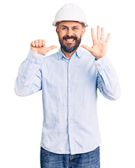 Young handsome man wearing architect hardhat showing and pointing up with fingers number six while smiling confident and happy.