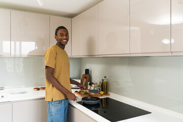 Happy african american man looking at camera with smile while holding frying pan