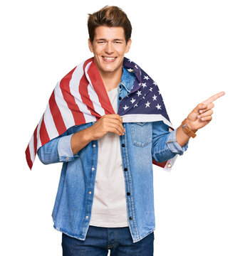 Handsome caucasian man holding united states flag smiling happy pointing with hand and finger to the side