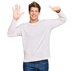 Handsome caucasian man wearing casual white sweater showing and pointing up with fingers number six while smiling confident and happy.