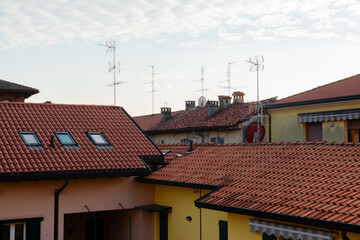 Tiled roofs of houses with antennas in a small town in Italy against the background of the evening sky