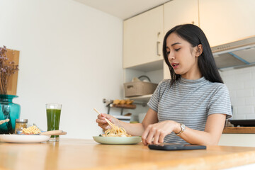 Obraz na płótnie Canvas Asian Girl  eating Thai food in kitchen counter Home delivery food feeling happy 
