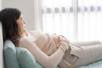 Pregnant asian woman holds hands on belly touching her baby caring about her health Beautiful happy...