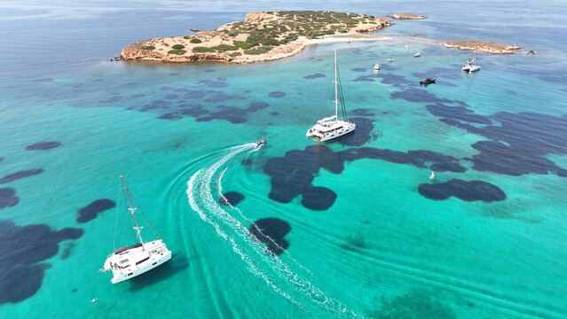 Aerial drone photo of famous small uninhabited island of Ydrousa or Katramonisi with crystal clear emerald sea perfect of yacht anchorage, Voula, Athens Riviera, Attica, Greece