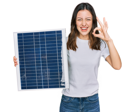Young beautiful girl holding photovoltaic solar panel doing ok sign with fingers, smiling friendly gesturing excellent symbol