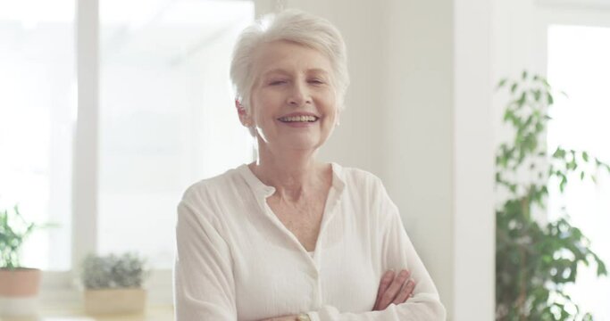 Happy, senior woman and arms crossed in home with pride and freedom in morning of retirement, holiday or vacation. Elderly, portrait and lady relax in kitchen, living room or house with sunshine