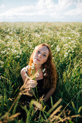 red-haired girl in a field with daisies