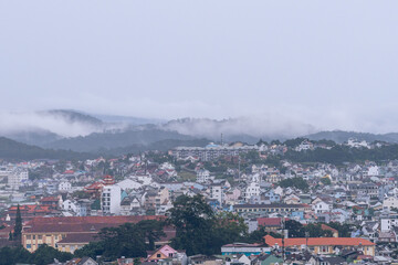 Obraz premium View on roofs in the city of Dalat. Da Lat and the surrounding area is a popular tourist destination of Asia. City with fogs and mountains