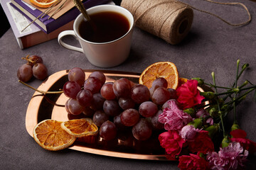Spring aesthetic cozy still life snacks with grapes, cup of coffee and flowers on the golden tray