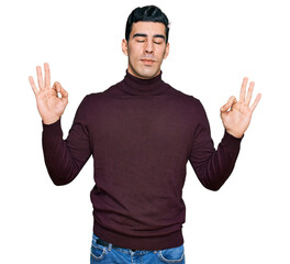 Handsome hispanic man wearing casual turtleneck sweater relax and smiling with eyes closed doing meditation gesture with fingers. yoga concept.