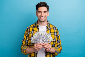 Portrait of successful positive guy with stubble wear checkered shirt hold bunch of dollars in arms...