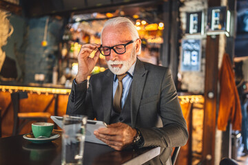 Senior man businessman business owner use digital tablet sit at cafe