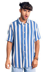 Young hispanic man wearing casual clothes in shock face, looking skeptical and sarcastic, surprised with open mouth