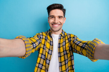Photo of attractive cheerful guy wear yellow checkered shirt smiling recording video vlog isolated...