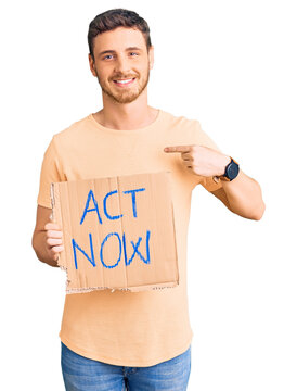 Handsome young man with bear holding act now banner pointing finger to one self smiling happy and proud