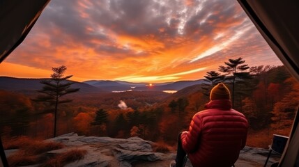 A man enjoys the view of the autumn mountains while sitting in a tent. Hiking and digital detox concept. Contemplation of nature alone with your thoughts. Peace and slow life. Alone with yourself