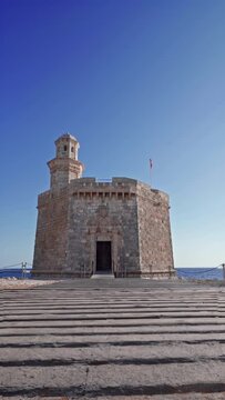 Sant Nicolau Castle in Ciutadella of menorca on the cliffs with blue summer sea and blue sky