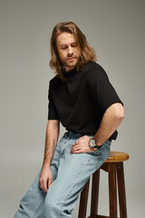 bearded and handsome man with long hair in jeans, tattoo translation: Love conquers all
