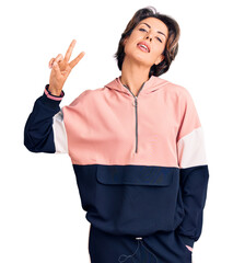 Young beautiful woman wearing sportswear smiling looking to the camera showing fingers doing victory sign. number two.