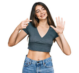 Obraz na płótnie Canvas Young beautiful teen girl wearing casual crop top t shirt showing and pointing up with fingers number seven while smiling confident and happy.