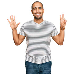 Hispanic adult man wearing casual clothes showing and pointing up with fingers number seven while smiling confident and happy.
