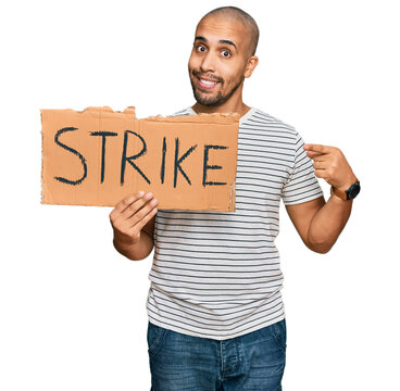 Hispanic adult man holding strike banner cardboard smiling happy pointing with hand and finger