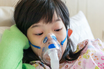 Sick little asian girl inhalation with nebulizer for respiratory treatment