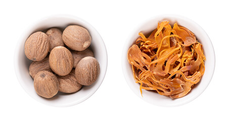 Dried true nutmegs and mace in white bowls. Whole seeds of Myristica fragrans, and the seed coverings of nutmeg seeds with yellow and orange tan. Used to flavor food and in preserving and pickeling.