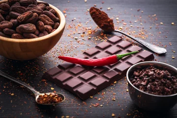 Keuken spatwand met foto Dark chocolate bar, red hot chilli pepper cayenne,  dry hot chili spices, cocoa beans nibs powder, food tasty design on black wooden background © ValentinValkov