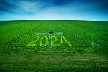 2024 Happy New Year concept and Aerial view of farming tractor plowing and spraying on field.