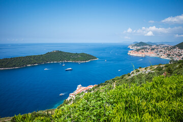 Fototapeta na wymiar Top view to Dubrovnik Old Town and Lokrum island in the Adriatic sea on sunny summer day. Focus on green bushes in the foreground 