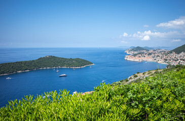 Top view to Dubrovnik Old Town and Lokrum island in the Adriatic sea on sunny summer day. Focus on green bushes in the foreground