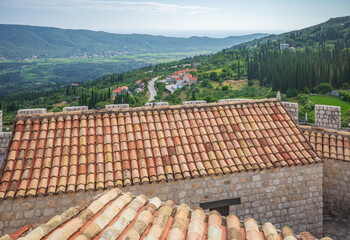 Top view to red tile roofs of Sokol fortress, Croatia, on background of the village and green hills

