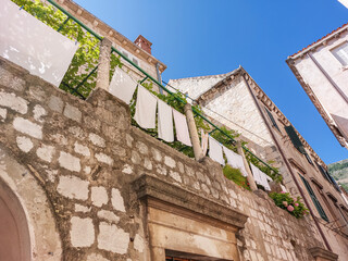Washed white linen hanging on the rope on balcony in the Dubrovnik Old Town on sunny and clear summer day