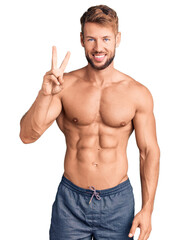 Fototapeta premium Young caucasian man standing shirtless showing and pointing up with fingers number two while smiling confident and happy.