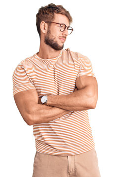 Young caucasian man wearing casual clothes and glasses looking to the side with arms crossed convinced and confident