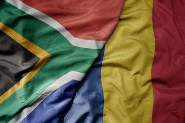 big waving national colorful flag of romania and national flag of south africa .