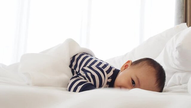 lovely asian male baby in black and white dress laying on the white bed