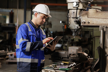 Male workers wearing uniform safety and hardhat  using tablet checking size an iron cutting machine in factory.