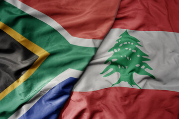 big waving national colorful flag of lebanon and national flag of south africa .
