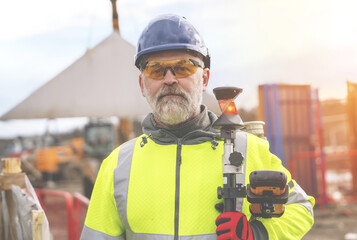 Closeup portrait of a Surveyor builder site engineer with theodolite total station at construction...