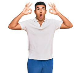 Young arab man wearing casual clothes looking surprised and shocked doing ok approval symbol with fingers. crazy expression