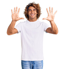 Young hispanic man wearing casual white tshirt showing and pointing up with fingers number ten while smiling confident and happy.