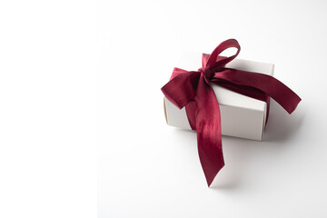 White gift box with red bow on white background with red hearts. Holiday banner. Top view. Happy Valentines Day